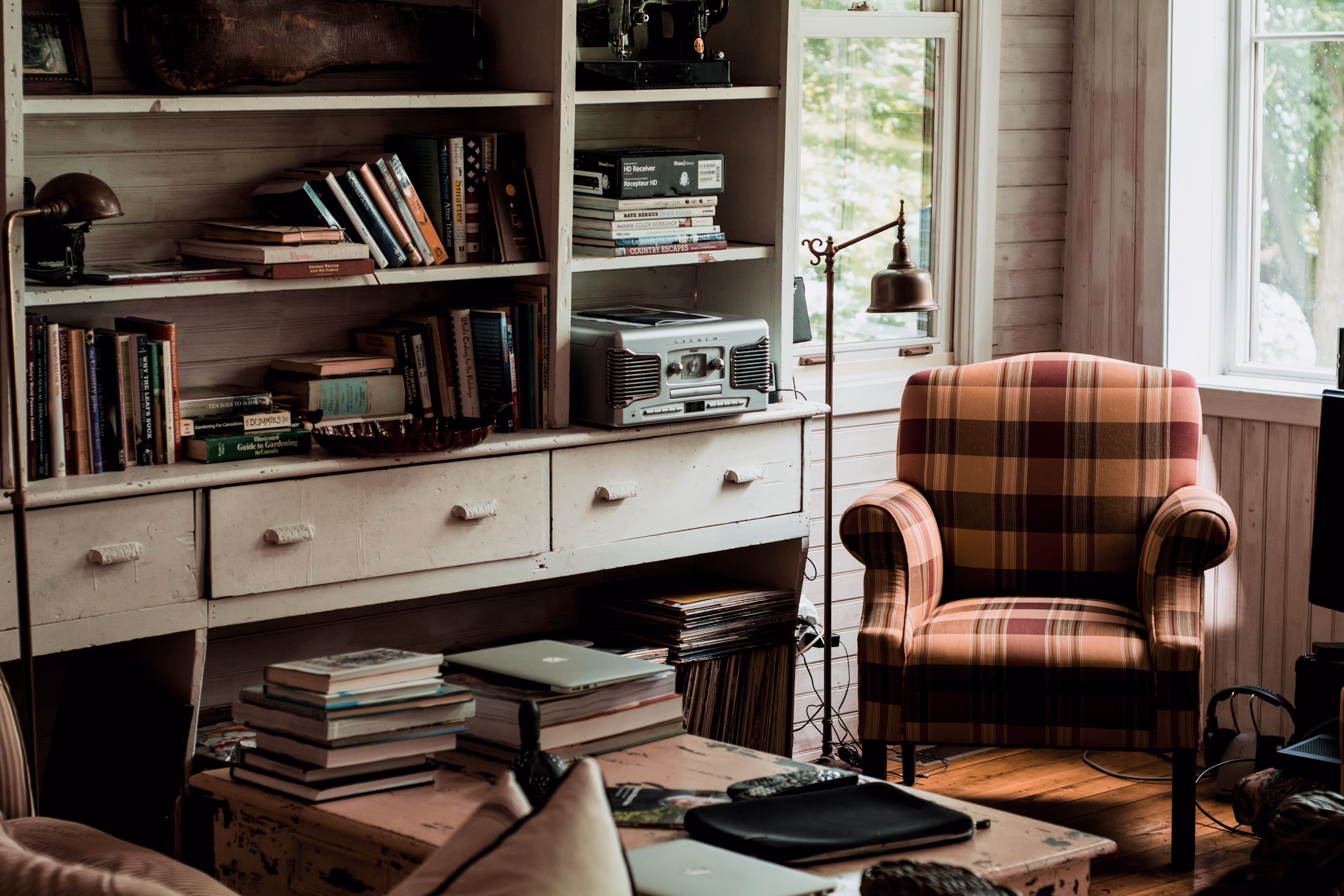 A cosy reading area with a red tartan chair and a white shelf fixture containing books and a record player.