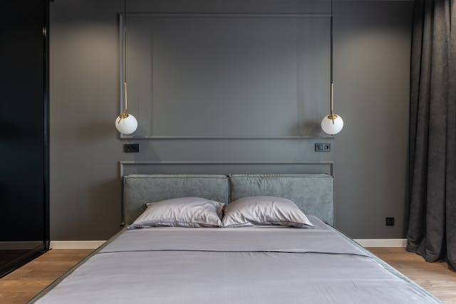 A photo of two pendant lights hanging next to a bed