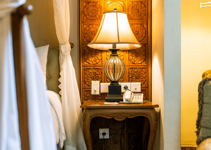 Stylish, rustic table lamp lit up against a wooden decor background