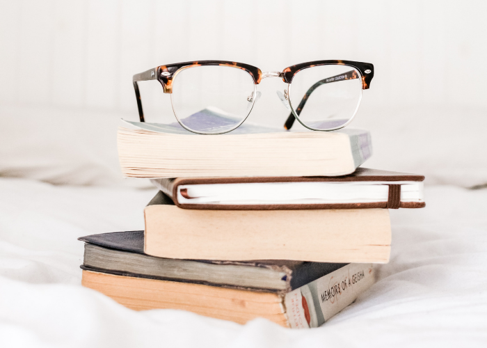 Books stacked on top of each other with a pair of reading glasses balanced on top